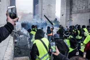 December 1st, 2018, Paris (75), FRANCE. Demonstrators, known as yellow jackets, attack policemen trying to hold position under the Arch of Triumph in Paris. They will manage to erect a barricade for a few moment under the arch of Triumph. Demonstrations were held everywhere in France. People from low class started to ask the government to give up on new gas taxes. Their claims being ignored they tend to ask for tax justice and more purchasing power.